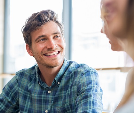 Man smiling with friend at restaurant