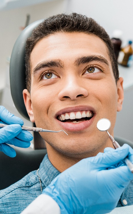 a smiling person having their teeth examined by a dentist