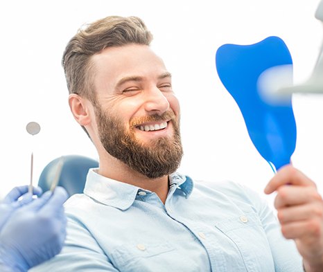 man smiling in dental mirror 