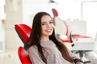 a patient smiling while sitting in the dental chair