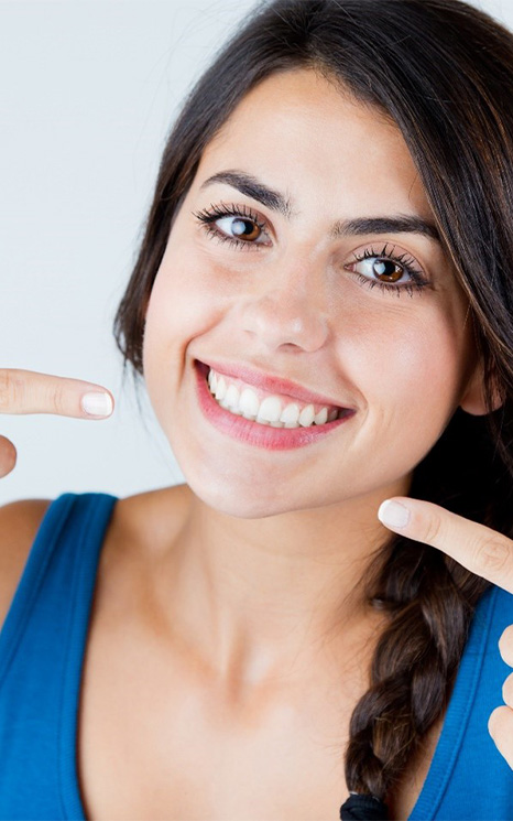 Young woman pointing to her smile