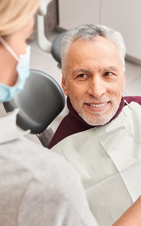 A dentist helping an elderly man get dentures in Burien