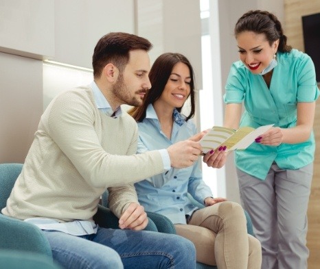 Dental team member and patients discussing emergency dentistry costs