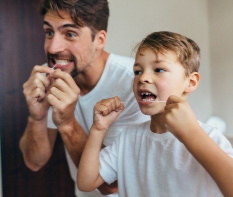 Father and child flossing teeth to prevent dental emergencies