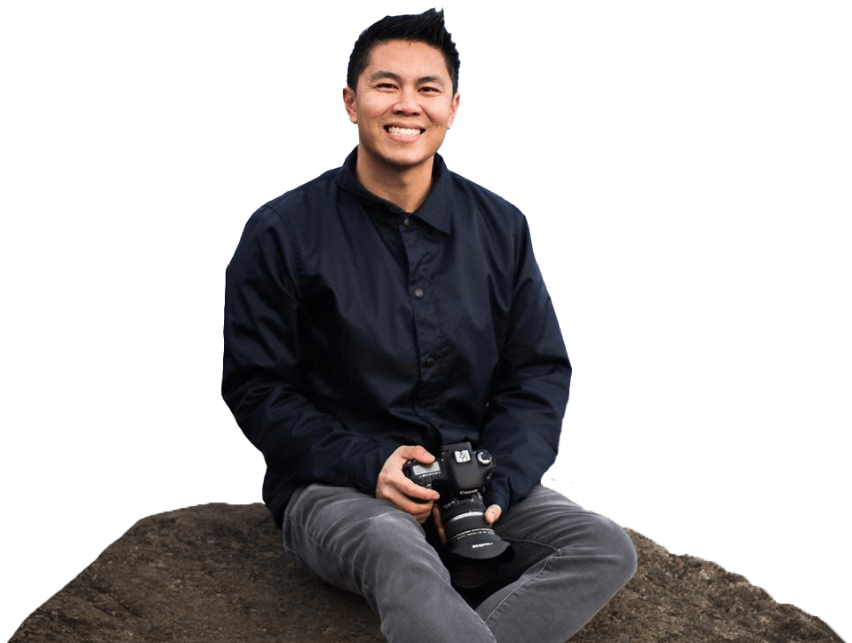 Burien Washington dentist Vincent Lam D M D sitting on rock and holding camera