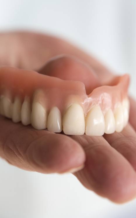 Hand holding a full denture