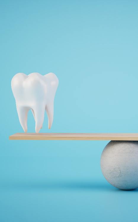 A 3 D illustration of a model tooth and gold coins on a balance beam