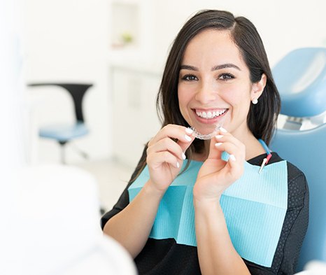 A dental patient holding a Candid Pro clear aligner