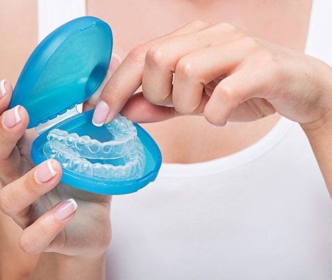 A young woman placing clear aligners in a storage case