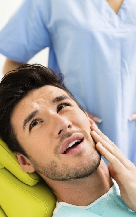 Man holding jaw in pain while seeing dentist for T M J treatment in Burien