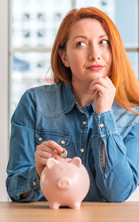 woman putting a coin into a piggy bank