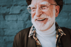 Fashionable man with white beard smiling on a blue background