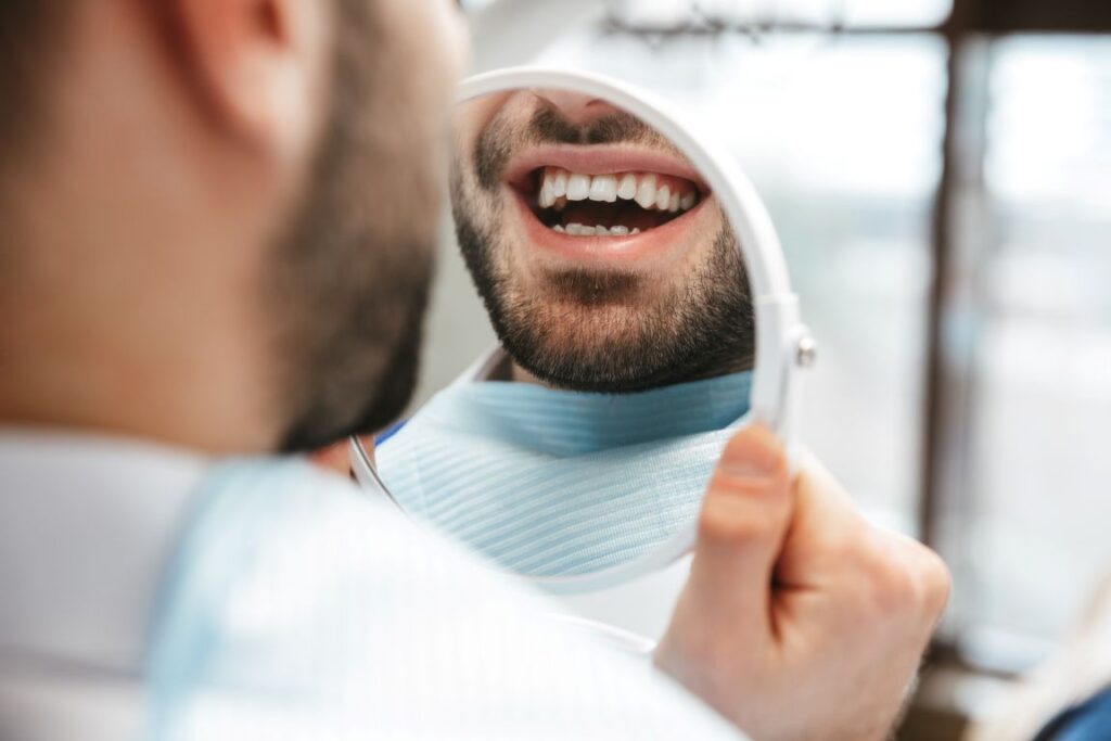 A man looking in the mirror at the dentist’s office